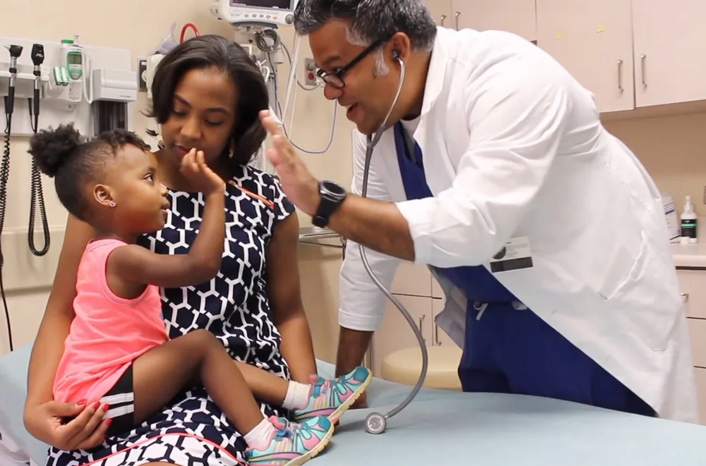 Dr. Bansal high-fiving a young patient during a pediatric exam